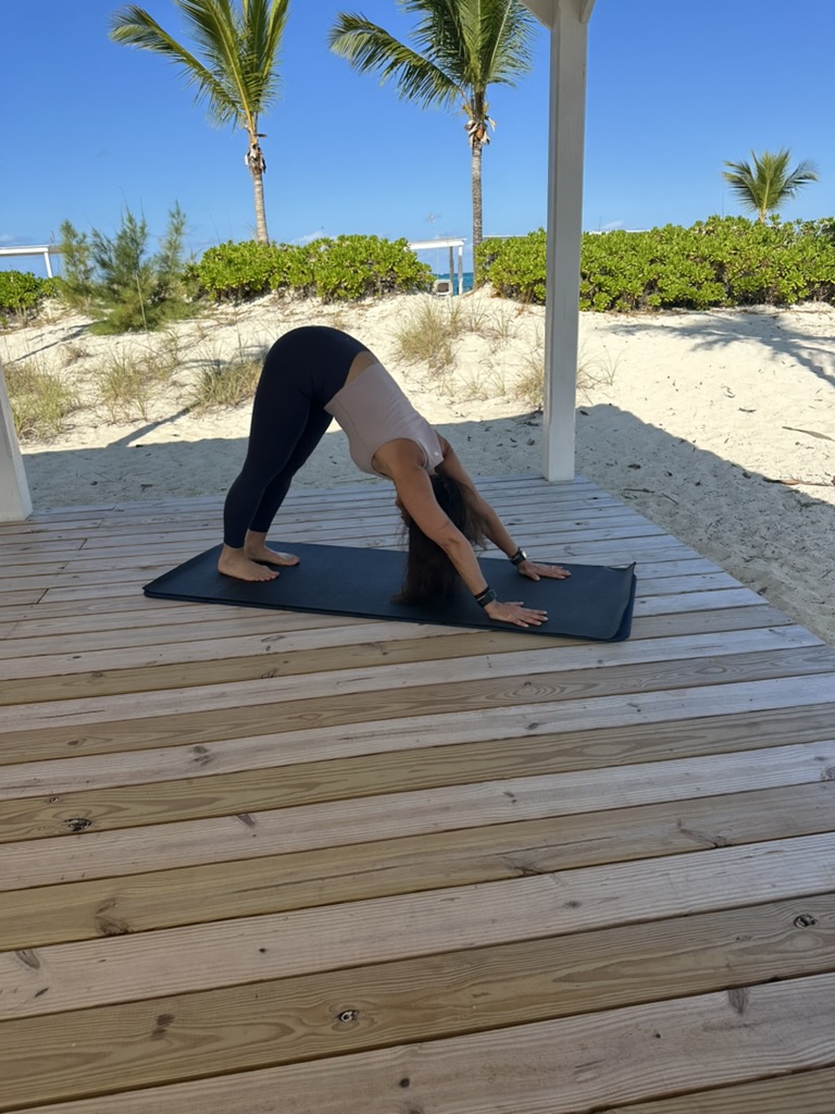 Marni in a downward dog yoga pose on a beach deck